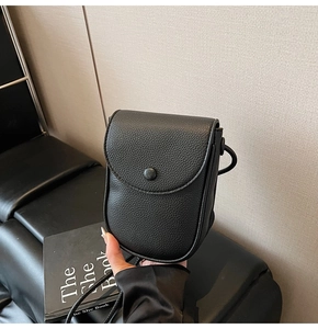 Détail d'un petit sac en cuir noir grainé avec rabat et boucle ronde décorative