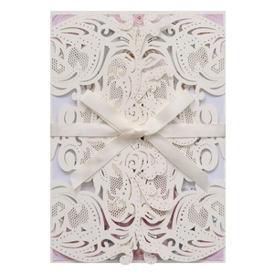 Close-up of laser cut hollow floral invitation cover with satin ribbon bow and insert