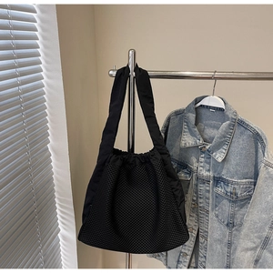Detail of black nylon mesh tote bag showing honeycomb texture and drawstring closure