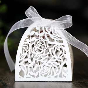 Detail of white laser-cut rose hollow favor box with elegant satin ribbon bow