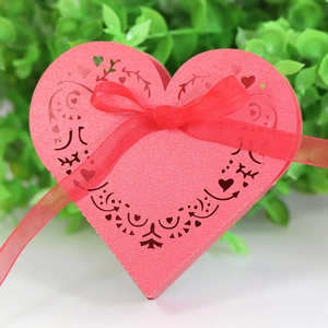 Detail of pink heart-shaped gift box with laser-cut patterns and red silk ribbon