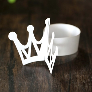 Detailed macro view of white crown paper napkin ring on dark wooden table surface