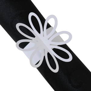 Detail showing white laser-cut floral paper napkin ring on black silk cloth