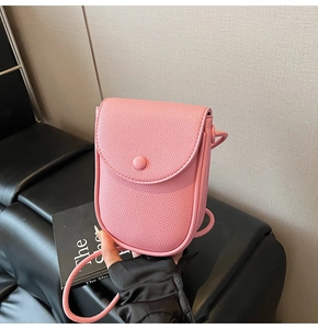 Détail d'un petit sac à bandoulière rose en cuir grainé avec rabat arrondi pour smartphone