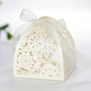 Detail of laser-cut white favor box with floral patterns and organza ribbon bow