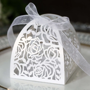 Close-up of white laser-cut rose candy box with an elegant silver ribbon on a plate