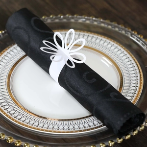 Close-up of white laser-cut floral napkin ring on a black napkin for wedding decor