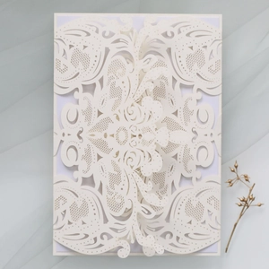 Macro view of white laser-cut floral invitation with damask pattern on mesh background