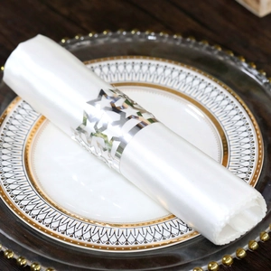 Close-up of shiny silver star cutout napkin ring on white satin and ceramic plate