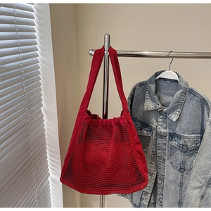 Detail of red mesh hollow-out tote bag with canvas straps hanging in a warm light setting
