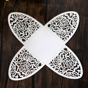 Flat lay of white laser-cut cardstock candy box with elegant rose patterns on wood surface