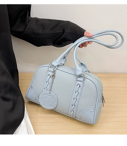 Detail of light blue lychee pattern leather handbag with lace-up straps and silver zipper