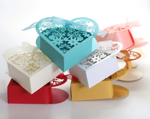 Detail of laser-cut heart candy boxes with floral patterns and silk ribbons in various colors