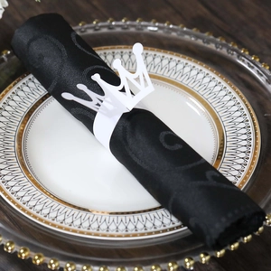 Detail view of a white paper crown napkin ring on a black napkin for table setting
