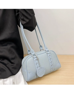 Close-up of light blue leather boston bag with woven details and silver metal rivets