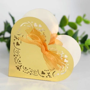 Detail of golden heart-shaped laser-cut gift box with intricate filigree and orange ribbon