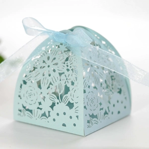 Detail of light blue laser-cut candy box with floral hollow patterns and organza ribbon
