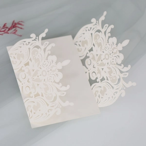 Detailed laser-cut wedding invitation featuring intricate floral lace patterns on ivory paper