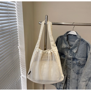 Close-up of white mesh tote bag with drawstring closure and wide canvas handle