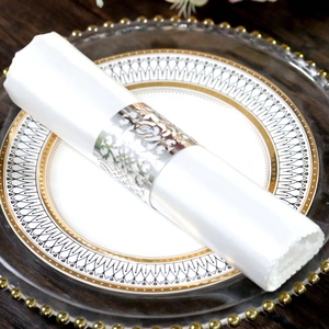 Detail of silver laser-cut hollow rose napkin ring on a white napkin over luxury tableware