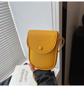 Gros plan du mini sac à bandoulière en cuir jaune vif avec texture grainée et rabat