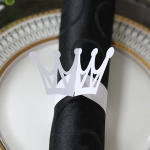 Detailed laser-cut white paper crown napkin ring on a premium black textured napkin