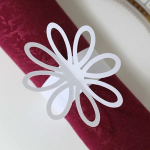 Detail of white laser-cut floral napkin ring with pearlescent finish on a red napkin