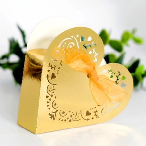Detail of laser-cut heart candy box with golden finish and orange organza ribbon
