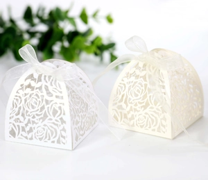 Close-up of laser-cut rose hollow favor boxes with elegant ribbon bows for weddings
