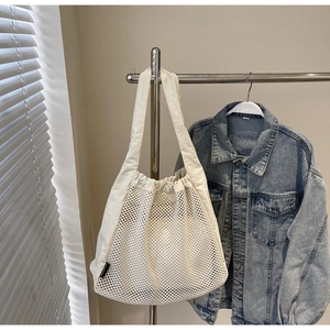 Detail view of large mesh nylon tote bag with drawstring closure and white canvas shoulder straps