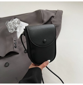 Détail du sac à téléphone en cuir noir grainé avec fermeture à rabat moderne
