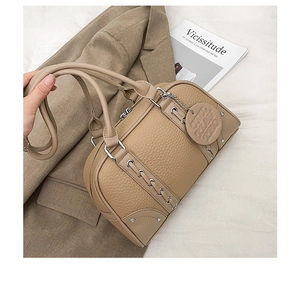 Detailed view of camel pebbled leather boston bag with metal buckle and hanging round tag