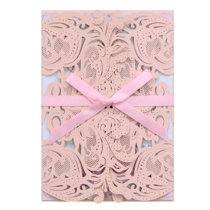 Pink laser-cut wedding invitation with elegant satin bow and intricate floral patterns