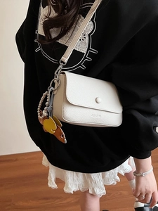 Minimalist beige crossbody square bag with lychee pattern leather worn by a model