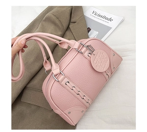 Detail of pink lychee leather Boston bag with silver hardware and braided strap accents