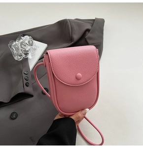 Détail de la texture en cuir rose grainé sur un mini sac à bandoulière pour portable