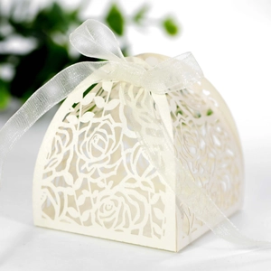 Detailed macro view of laser-cut cream wedding favor box with ribbon and rose patterns