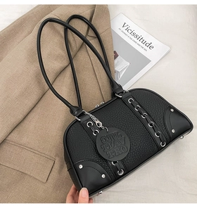 Close-up of black lychee leather bag with silver rivets and branded round tag detail