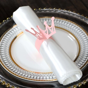 Pink crown paper napkin ring on a white satin napkin with golden table setting