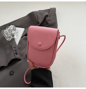 Gros plan d'un sac à bandoulière rose en cuir texturé tenu par un mannequin en scène