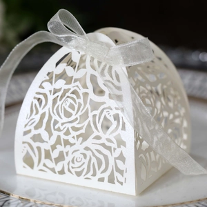 Detail of laser-cut rose hollow pattern on white favor box with elegant silk ribbon