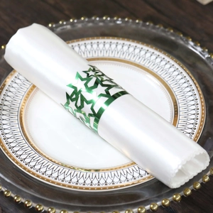 Close-up of green star napkin ring on white silk napkin with elegant gold-rimmed plate