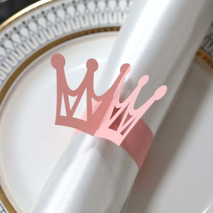 Close-up of pink crown napkin ring with laser-cut detail on a satin napkin