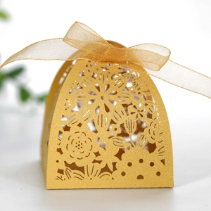 Macro shot of laser-cut gold gift box featuring intricate floral patterns and silk ribbon