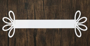 Detailed view of white paper napkin ring with floral hollow cutouts on dark wood background