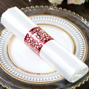 Close-up of red rose hollow napkin ring with metallic luster on white rolled napkin