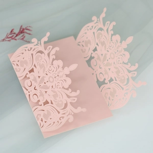 Detail of pink laser-cut wedding invitation card with intricate floral patterns