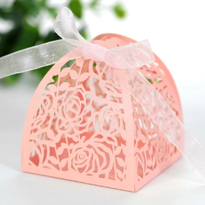 Close-up of pink laser-cut favor box with rose patterns and elegant organza ribbon