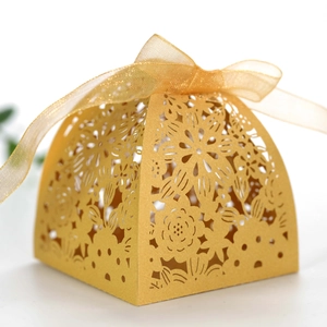 Detailed close-up of a laser-cut gold wedding favor box with an elegant ribbon bow