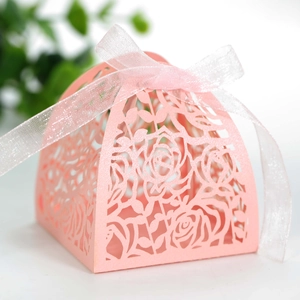 Close-up of pink laser-cut rose hollow gift box with a white organza ribbon bow